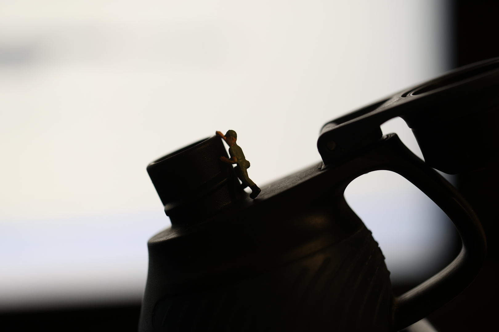 Picture of a H0 mini figure climbing a drinking flask in front of a bright background